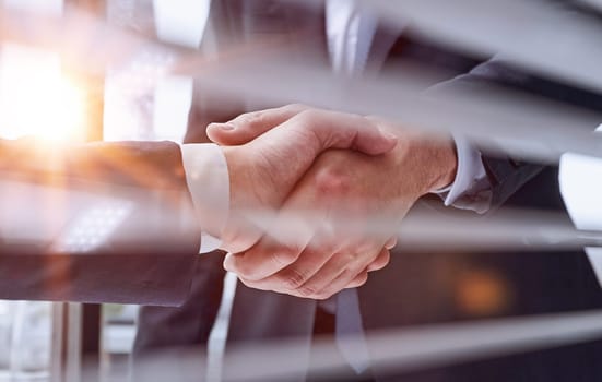 Two business people shaking hands in front of their colleagues