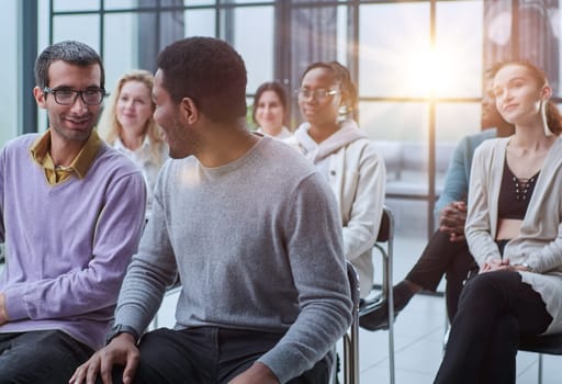 A group of people at a business meeting. The team leader talks to his employees and colleagues. Young men and women listening to a speaker