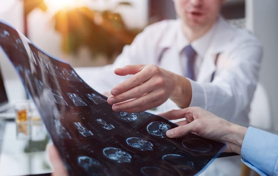 Young man looking at one of x-ray results being shown by his doctor