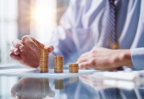 Business, Money, Finance, Secure and Saving Concept. Close up of man hand holding and put a coin to stack of coins table.