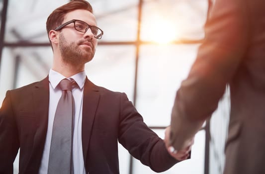 Friendly male professional colleagues greeting handshaking meeting in company office hall