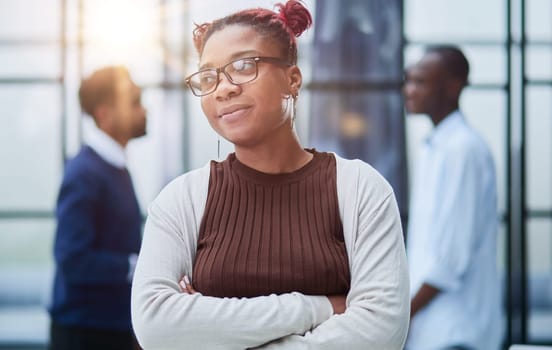 She is standing in a modern office with her colleagues in the background.