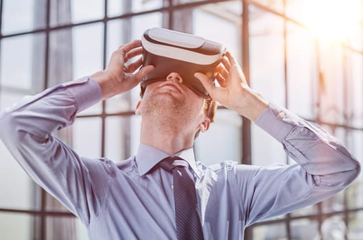 young man testing VR glasses or goggles sitting in the office room