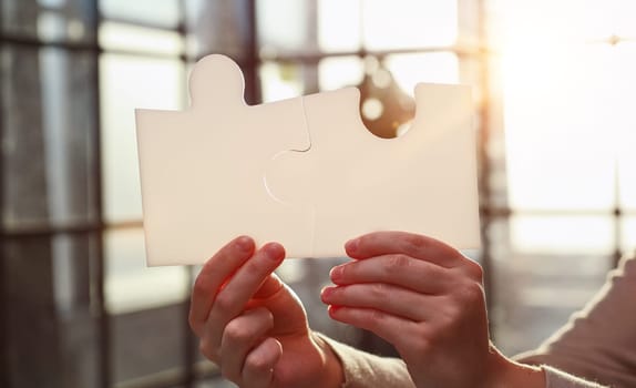 Business Woman holding two blank white puzzle pieces in his hands conceptual of solving a problem