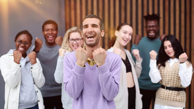Cheerful business colleagues clenching fists celebrating victory in office