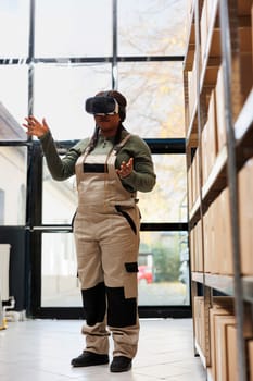 Stockroom manager working at merchandise inventory using virtual reality headset in storage room. African american worker preparing packages for delivery, using 3d simulation for customers orders