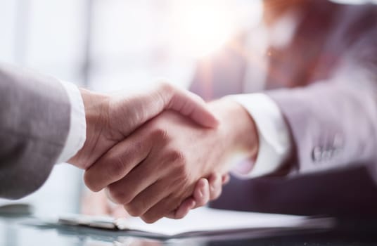 Photo of business handshake over workplace in office