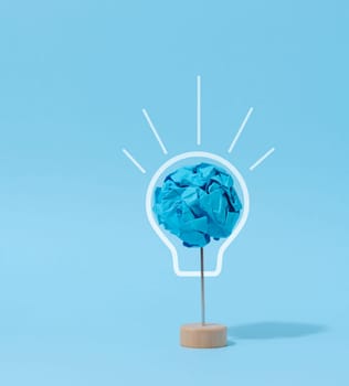 A crumpled ball of blue paper, a drawn electric lamp. New idea concept