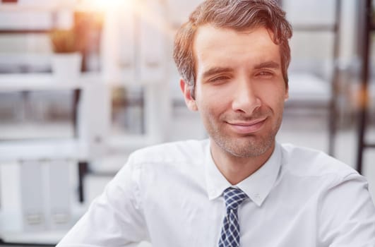 Confident young businessman posing in the office with his hands together