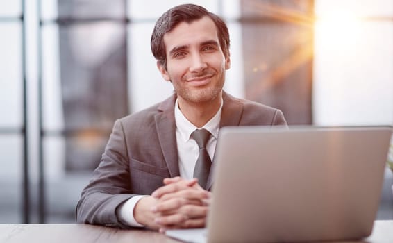 Young man using laptop and smiling at the office