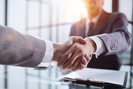 Man shaking hands with partner over office desk