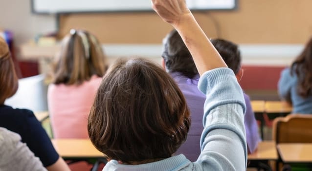Back view of older student raising his hand to answer teacher's question during education training class. jpg ai image. High quality image