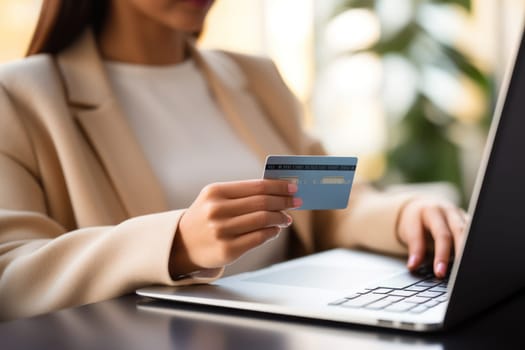 Close-up of female hand holding credit card and laptop making Internet purchase.