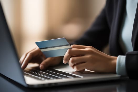 Close-up of female hand holding credit card and laptop making Internet purchase.