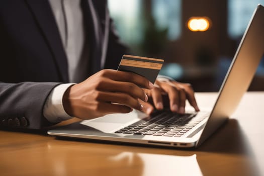 Close-up of female hand holding credit card and laptop making Internet purchase.