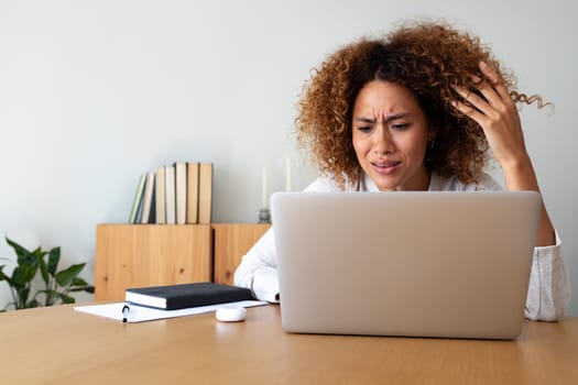 Multiracial hispanic woman feeling angry and frustrated while working with laptop at home office. Copy space. Lifestyle concept.