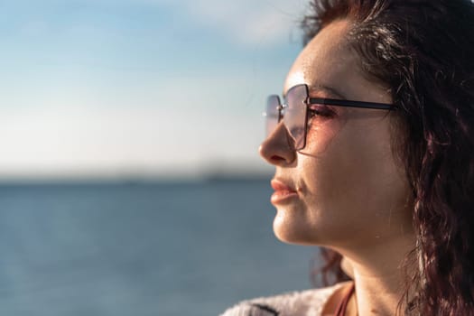 Portrait of a curly woman in glasses on the background of the sea. Vacation on the sea, walk, tourism