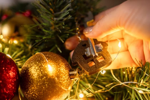 Gift key house with a keychain in hand backdrop of Christmas tree. Building, design, project, moving to new house, mortgage, rent and purchase real estate. A gift for New Year, Christmas