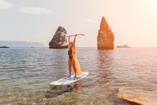 Close up shot of beautiful young caucasian woman with black hair and freckles looking at camera and smiling. Cute woman portrait in a pink bikini posing on a volcanic rock high above the sea