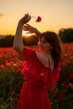 Woman poppy field red dress sunset. Happy woman in a long red dress in a beautiful large poppy field. Blond stands with her back posing on a large field of red poppies.