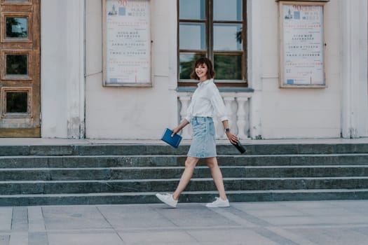 Woman staircase city. A business woman in a white shirt and denim skirt walks down the steps of an ancient building in the city.