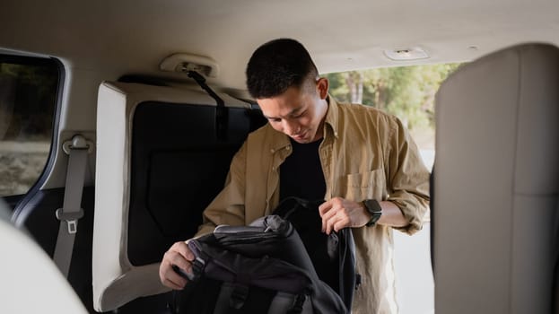 Man loading bags in a car trunk getting ready to leave on holiday vacation. View from the vehicle interior.