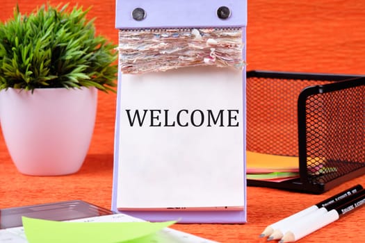 Business Concept. Welcome text written on the page of the desktop calendar on an orange background