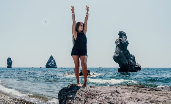 Woman travel sea. Young Happy woman in a long red dress posing on a beach near the sea on background of volcanic rocks, like in Iceland, sharing travel adventure journey