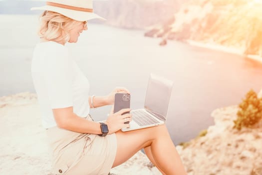 Digital nomad, Business woman working on laptop by the sea. Pretty lady typing on computer by the sea at sunset, makes a business transaction online from a distance. Freelance remote work on vacation