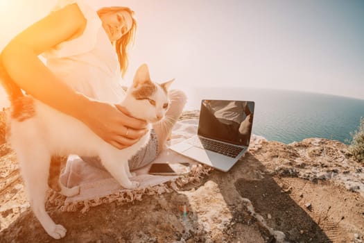 Woman sea laptop. Business woman in yellow hat working on laptop by sea. Close up on hands of pretty lady typing on computer outdoors summer day. Freelance, digital nomad, travel and holidays concept.