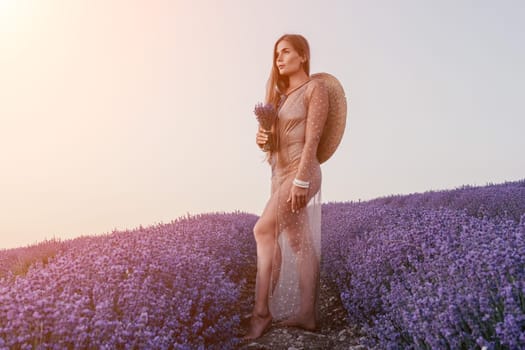 Close up portrait of young beautiful woman in a white dress and a hat is walking in the lavender field and smelling lavender bouquet.