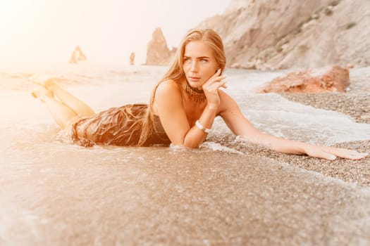 Woman travel sea. Young Happy woman in a long red dress posing on a beach near the sea on background of volcanic rocks, like in Iceland, sharing travel adventure journey