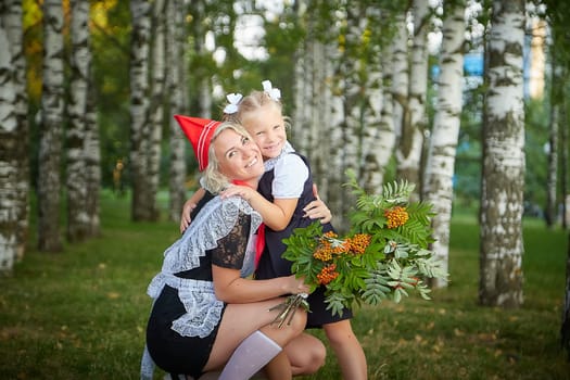 Young and adult schoolgirl on September 1 with flowers. Generations of schoolchildren of USSR and Russia. Female pioneer in red tie and October girl in modern uniform. Daughter and Mother having fun