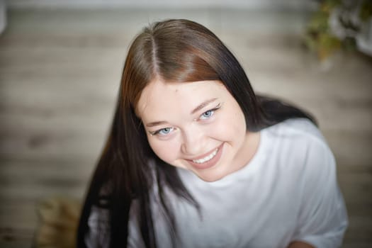 People and lifestyle concept. Body positivity. Indoor portrait of positive young Caucasian girl with chubby cheeks enjoying at home, smiling happily