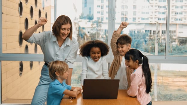 Group of diverse student and teacher celebrate successful project. Happy caucasian instructor looking at engineering code and cheering and encourage learner to improve skill at STEM class. Erudition.