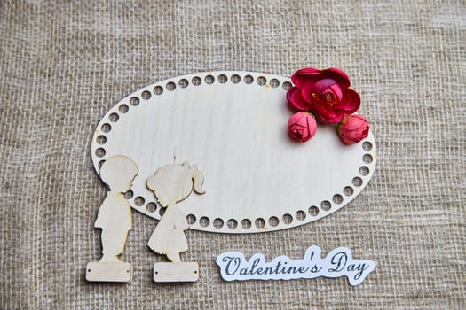 Wooden figurines of couple, inscription Valentine's Day, red flowers. Concept of holiday of love. Background, texture, frame, place for text, copy space
