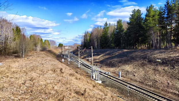 Railway track in the spring forest with blue sky. Concept of travel and trip