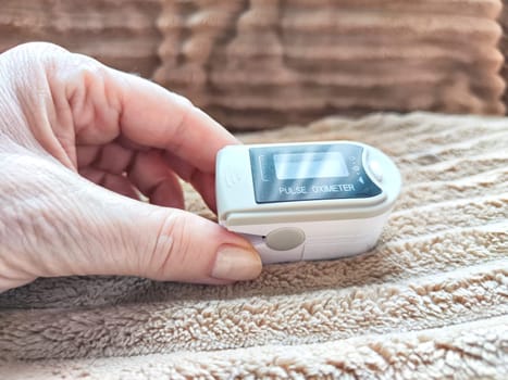 Close up of hand with a pulse oximeter on the finger.