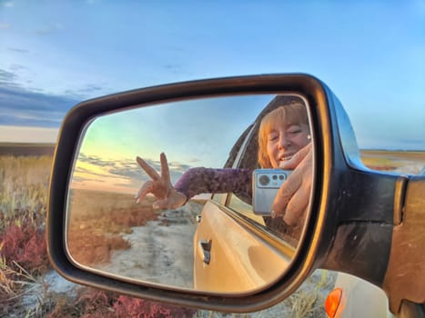 Self portrait at side view mirror of a car in travel, trip on nature