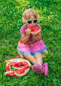 Child girl in the park eats watermelon. Selective focus. Food.