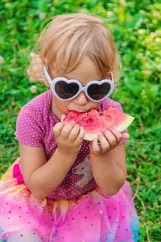 Child girl in the park eats watermelon. Selective focus. Food.