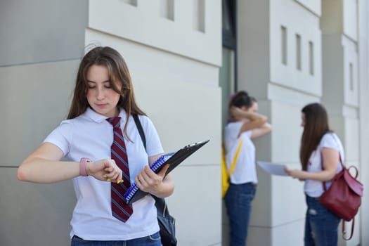 Girl student looks at wristwatch, college education, outdoor teens students.