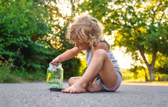 The child holds a grasshopper in his hands. Selective focus. Nature.