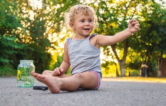 The child holds a grasshopper in his hands. Selective focus. Nature.