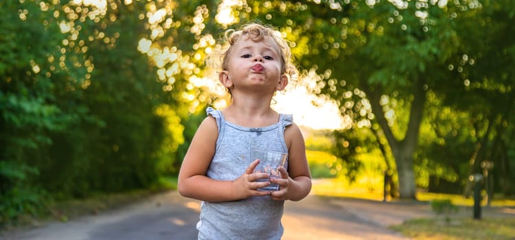 A child drinks water from a glass. Selective focus. Kid.