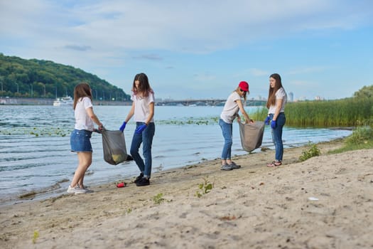 Group of students with teacher in nature doing cleaning of plastic garbage. Environmental protection, youth, volunteering, charity, and ecology concept