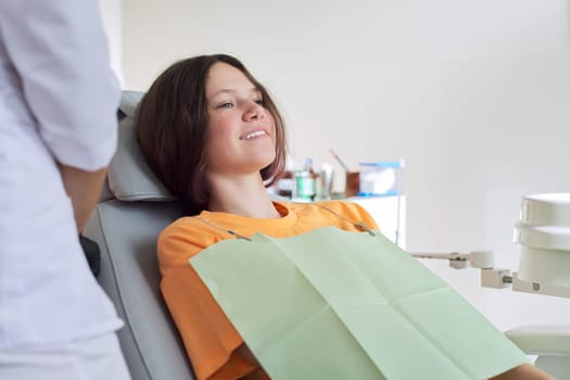 Young girl treating teeth, female teenager sitting in dentists chair. Dentistry, healthy teeth, medicine and healthcare concept, copy space