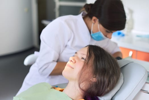 Young girl treating teeth, female teenager sitting in dentists chair. Dentistry, healthy teeth, medicine and healthcare concept