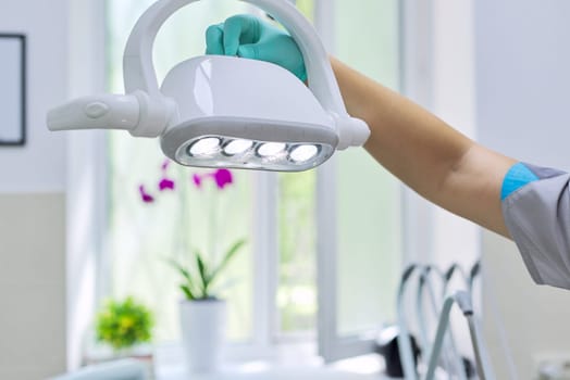 Dental chair led lamp, close-up modern medical professional equipment in dentist office. Female doctor touching lamp