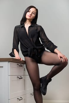Posing beautiful young woman in black nylon tights and stylish leather boots, female showing legs, shoe fashion